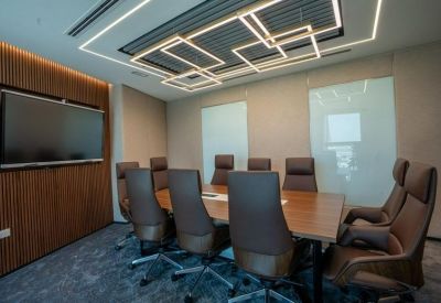 Professional meeting room with a wooden table, leather chairs, and square ceiling lights.