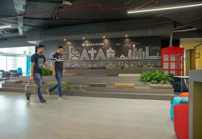 Spacious coworking area with tiered wooden seating and a Doha skyline mural.
