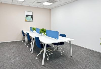 Co-working area with white workstations, blue chairs, and grey carpeting.