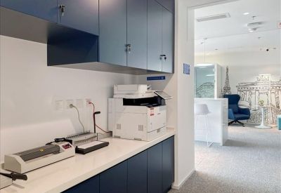 Office utility station with navy cabinetry, a printer, and binding equipment.