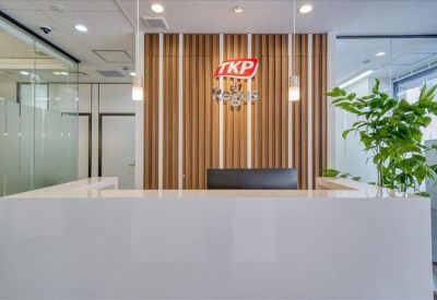 Professional reception desk in white with wood-slat feature wall and branded logo.