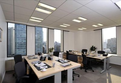 Brightly lit open-plan office with multiple desks and large windows.