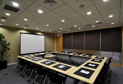 Large professional boardroom with U-shaped table and projector screen.