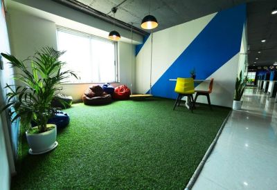 Spacious communal breakout area with artificial grass flooring, bean bags, and a blue geometric feature wall.