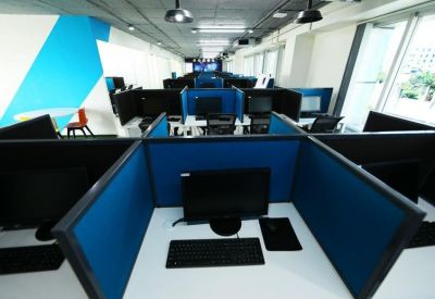 Open-plan workspace with blue-partitioned cubicles and modern computer workstations.