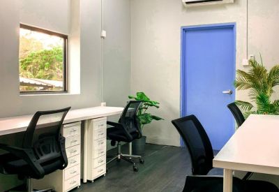 Private office suite with multiple workstations, ergonomic chairs, and a bright blue door.