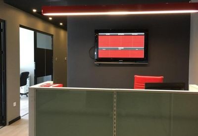 Modern reception desk with a dark feature wall, red light fixture, and digital display.