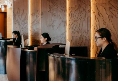 Modern reception area with staff at sleek black desks against a textured wood-panelled wall.