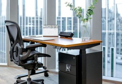 Modern ergonomic workstation with an adjustable desk positioned in front of a floor-to-ceiling window.