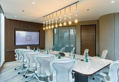 Professional boardroom featuring white ergonomic chairs and a row of designer pendant lights.