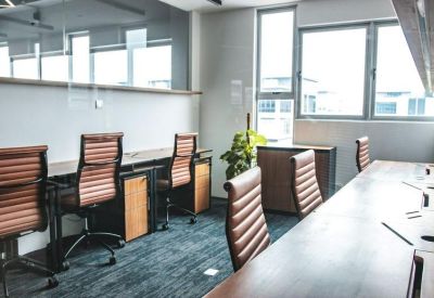 Bright office space with rows of ergonomic leather chairs and wooden desks.