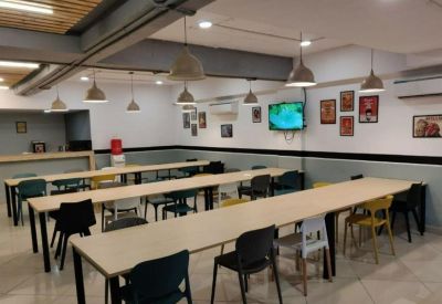 Long communal dining tables with colorful chairs and modern pendant lighting in a breakout area.