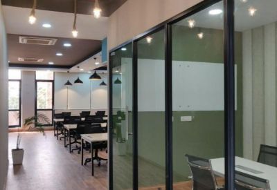 Hallway view of a modern office space in Sector 32, Gurgaon, Gurugram with glass-partitioned meeting rooms.