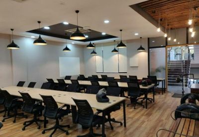 Professional meeting room with long wooden tables and black ergonomic chairs.