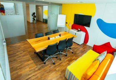 Vibrant meeting room with a wooden table, colorful wall murals, and a yellow sofa.