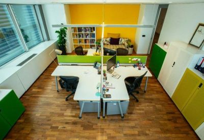 Bright open-plan office with T-shaped white desks and ergonomic chairs.