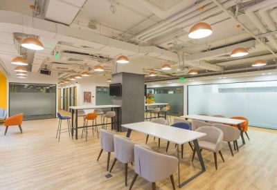 Bright communal dining and coworking area with modern seating and exposed ceilings.