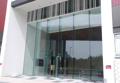 Modern glass entrance doors leading into a bright building lobby.