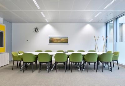 Spacious boardroom with a long white table and green upholstered chairs.