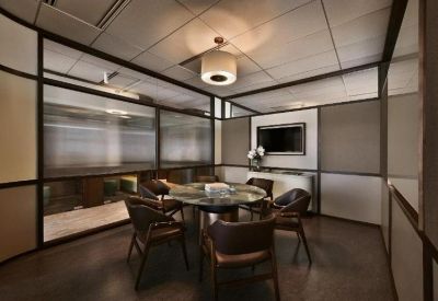 Private four-person meeting room with glass walls and contemporary dark wood chairs.