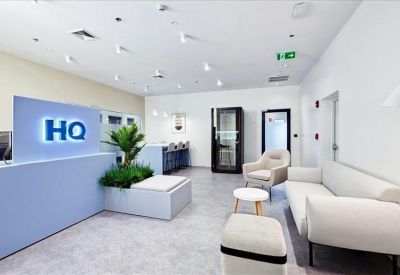 Contemporary office lounge with a white sofa, armchair, and indoor plants.