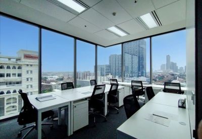 Spacious corner office with white desks, ergonomic chairs, and expansive urban views.