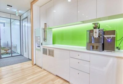Clean office pantry and coffee station featuring a bright green backsplash.