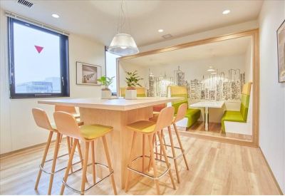 Modern break area with high-top wooden tables, bar stools, and a city-themed mural.