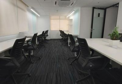 Spacious office environment with multiple white desks, black chairs, and dark carpet.