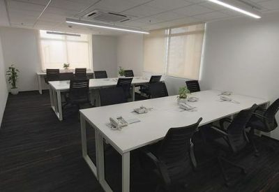 Meeting room with two long white tables, black mesh chairs, and overhead tube lighting.