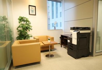 Lounge area with tan armchairs, a side table, and a large multi-function printer.