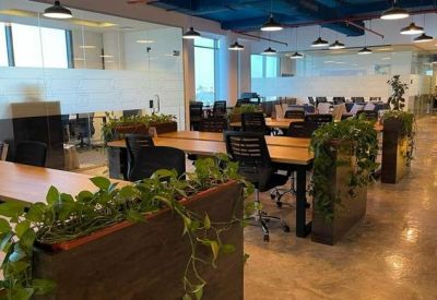 Large open-plan coworking space with wooden desks, integrated planters, and modern blue ceilings.