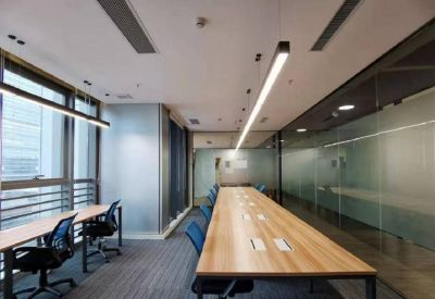 Bright long-table workstation area with blue chairs and linear overhead lighting.
