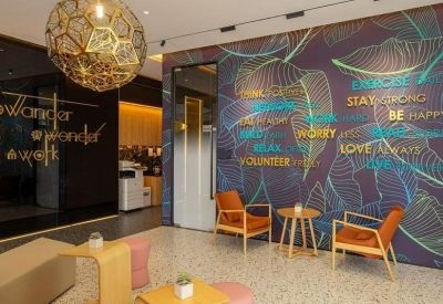 Colorful lounge area with a tropical leaf mural, orange armchairs, and a large geometric pendant light.