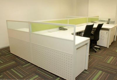 Modern office workstations with white desks and green privacy dividers.