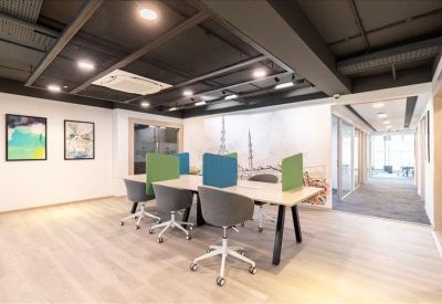 Modern coworking area with grey chairs and vibrant green and blue privacy dividers.