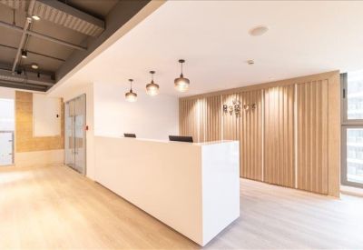 Bright reception desk with minimalist white finishes and warm wood-paneled walls.