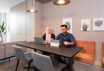 Two people working at a table in a modern communal lounge area.