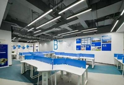 Open-plan office area with blue-partitioned desks and modern strip lighting.