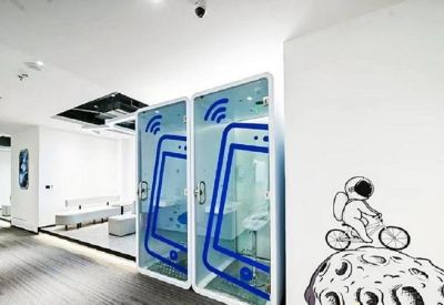 Modern hallway featuring glass phone booths and a playful astronaut wall decal.