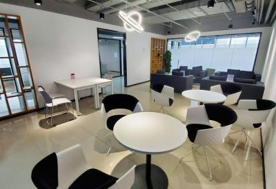 Communal lounge area with round white tables, modern black and white chairs, and planetary light fixtures.
