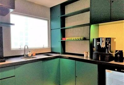 Modern teal kitchenette featuring a sleek black countertop and a high-end coffee machine.