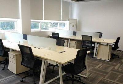 Open-plan office area with white desks and partition screens.