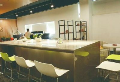 Bright communal break area featuring a long wooden bar counter and colorful seating.