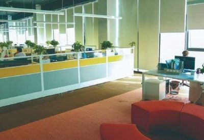 Open-plan office space with partitioned workstations and a modern red circular lounge seat.