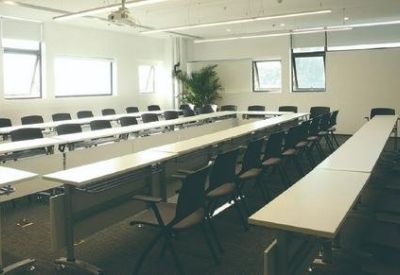 Large professional meeting room arranged in a U-shape with white tables and black chairs.