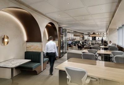Bright coworking space featuring wooden desks and comfortable grey ergonomic chairs.