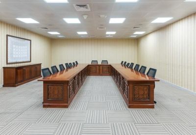 Large boardroom featuring a U-shaped wooden table and modern black chairs.