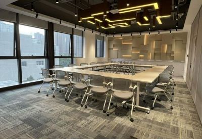 Spacious meeting room with a large square table and a creative geometric light fixture on the ceiling.