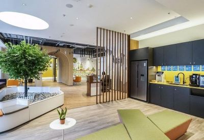 Lounge area featuring a large indoor tree, wooden slat partitions, and a small kitchenette.